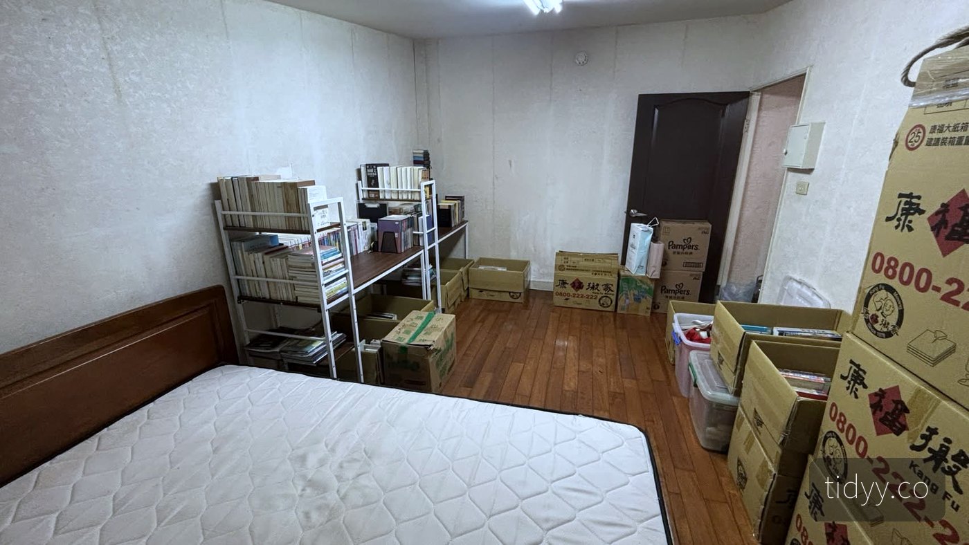 整理後的同一間儲藏室，書籍分類上架，地面清出一條走道，剩餘紙箱集中收攏在門邊