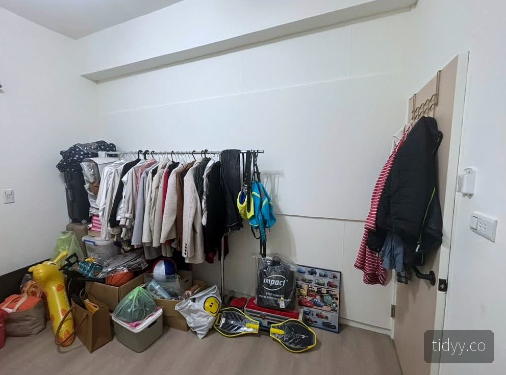 整理前的衣物間，吊桿上衣服擠成一團，地面堆滿紙箱、玩具與運動用品